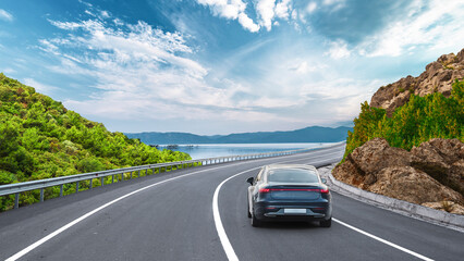 Electric car on the coast road on the shore of the sea. car driving on the road of europe. Highway view on the coast on the way to summer vacation. Germany trip on beautiful travel road landscape.