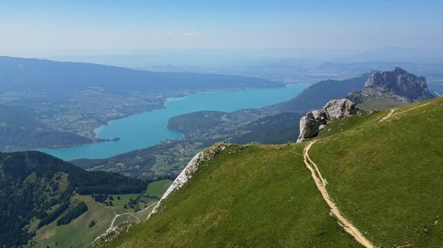 Drone aerial panorama of Lake Annecy and French Alps mountains with paragliders soaring above blue alpine lake, scenic summer travel destination in Haute-Savoie, France