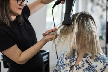 Hair Stylist Blow-Drying Client’s Hair in Salon