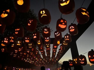 Glowing carved jack-o’-lanterns hanging in rows at dusk, creating a spooky and festive Halloween atmosphere under the night sky