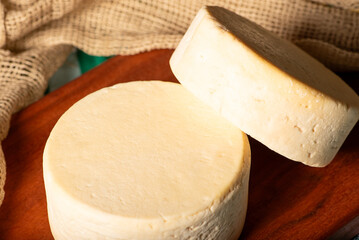 Semi-cured cheese made in Minas Gerais, Brazil, on a rustic surface and dark background, selective...