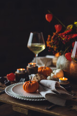 Beautiful elegant table setting for candlelight Thanksgiving Day dinner or Halloween party at home. Fancy dishware, porcelain plates. Floral centrepiece, pumpkins and burning candles as decor