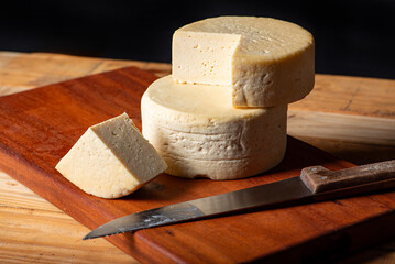 Semi-cured cheese made in Minas Gerais, Brazil, on a rustic surface and dark background, selective focus.