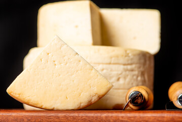 Semi-cured cheese made in Minas Gerais, Brazil, on a rustic surface and dark background, selective...