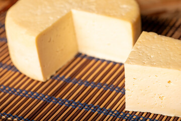 Semi-cured cheese made in Minas Gerais, Brazil, on a rustic surface and dark background, selective focus.