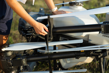 A close-up shot of a woman preparing agriculture drone by adjusting its wings, showcasing her...