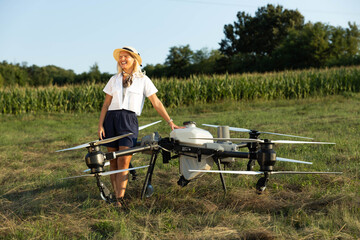 A joyful woman stands next to a large agriculture drone in a sunny field, showcasing innovation and...