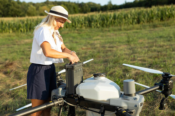 A happy woman smiles while working on her drone, installs a battery in a large agricultural drone....