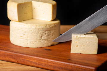 Semi-cured cheese made in Minas Gerais, Brazil, on a rustic surface and dark background, selective focus.