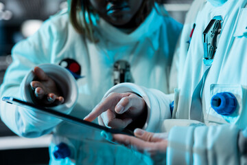 Astronauts looking at tablet interface showing orbital path to ensure safe operation during long distance space travel. Cosmonauts analyzing mission logs in spaceship during cosmic journey