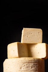 Semi-cured cheese made in Minas Gerais, Brazil, on a rustic surface and dark background, selective focus.