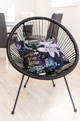 Modern black circular chair with decorative pillow featuring floral design