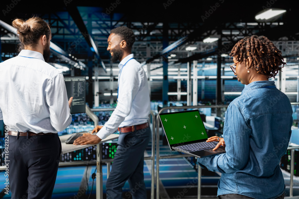 Poster african american female supervisor reviewing green screen on laptop, updating server racks infrastru