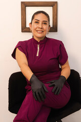 Portrait of a Colombian cosmetologist, wearing black gloves and a burgundy uniform, posing with a...