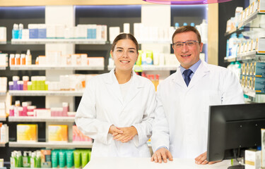 Man and girl pharmacists are standing in pharmacys sales hall, pharmacy staff are amicably...