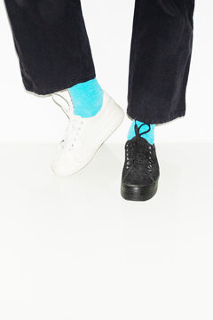 Person with blue socks and different pair sneakers trainers shoes
