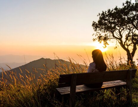 A woman sits on a bench, overlooking a sunrise over a mountain range