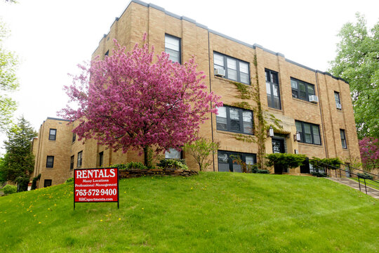 Beautiful blossoming fruit tree and a rental sign on the green lawn of an apartment building. St Paul Minnesota MN USA