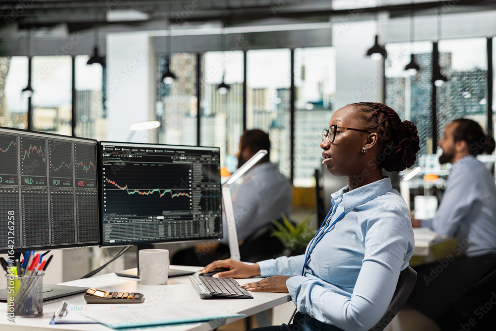 Poster trader in prop firm office monitoring stock market prices on multiple screens, trading securities. f
