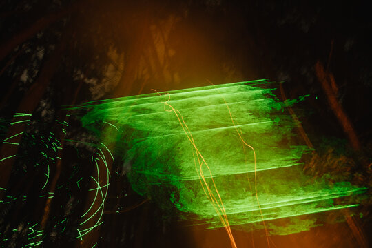 Light Trails Create Vibrant Patterns in a Forest at Night