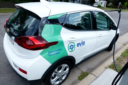 Chevy Bolt EV an Evie Community Carshare car parked on a neighborhood street being charged at a Spot charging station. St Paul Minnesota MN USA