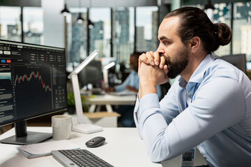 Stockbroker looking at stock exchange graphs, bummed by poor portfolio performance. Brokerage...