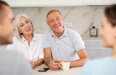 Young married couple and senior parents talk about home life