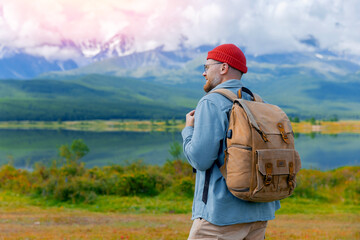 Young caucasian male traveler with backpack enjoying stunning mountains and lake reflection, relax...