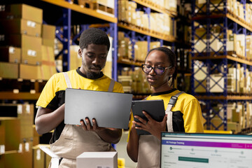 Black industrial workers reviewing goods information during shipment process. Team in depot...