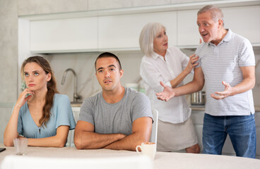 Elderly parents make claims to young couple in home kitchen