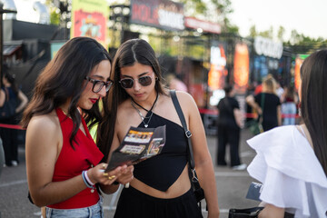 Young female friends checking food options at outdoor festival