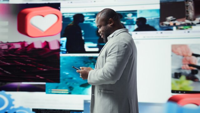 Happy person uses phone, doing engagement with multimedia content, sending likes. Joyous man browsing social networks feed on smartphone in front of dashboard featuring videos, camera A
