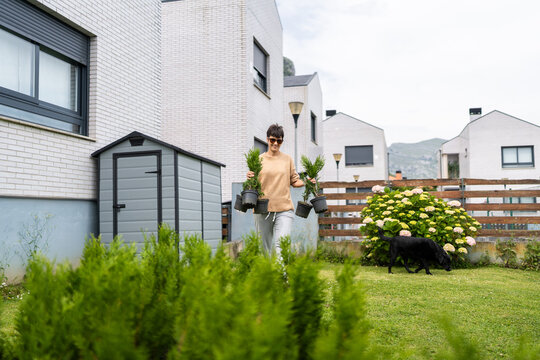 Woman carrying potted plants in her backyard garden