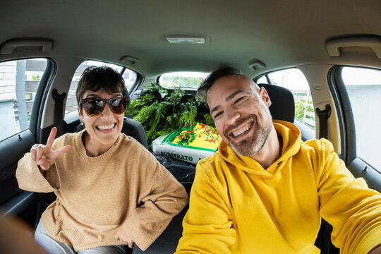 Couple taking selfie in car after buying plants and soil