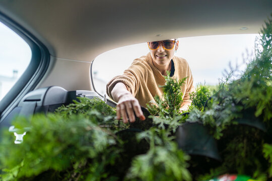 Woman arranging plants in car trunk after buying at garden center