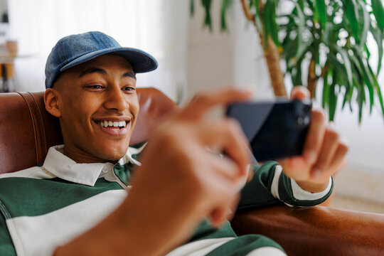 Happy man playing video games on smartphone at home