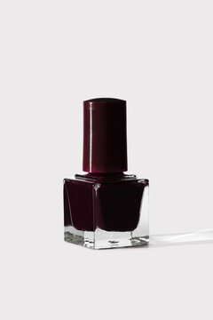 Deep burgundy nail polish in a clear bottle on white
