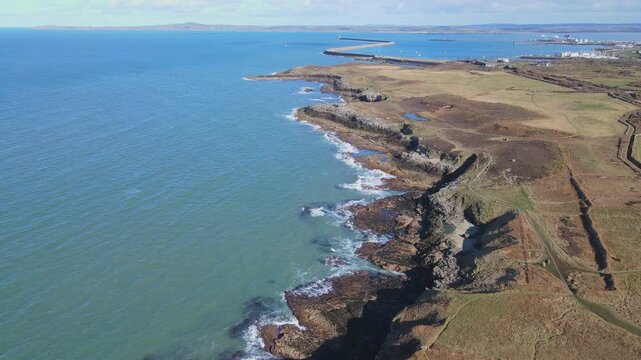 Drone over shoreline with waves crashing on rocks straight panning shot, Holyhead, Anglesey, Wales, 4K, 60fps