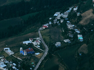Drone view of a rural community landscape in Mexico, showcasing colorful houses, farmland, and natural surroundings that reflect traditional lifestyle and cultural heritage.