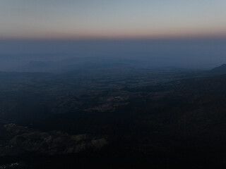 Drone view of a breathtaking mountain landscape above the clouds, showcasing rugged peaks and serene valleys in a stunning high-altitude natural scene.