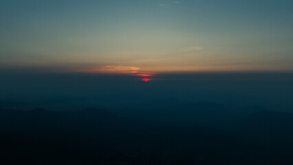 Drone view of a breathtaking mountain landscape above the clouds, showcasing rugged peaks and serene valleys in a stunning high-altitude natural scene.