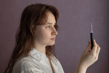 Obraz premium Ear Cleaning Technology, woman uses Digital Ear Scope, Earwax Cleaner With Gyroscope, Camera, Light. Cleaning Ears Device Connected to Smartphone