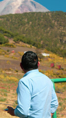A person gazes at the towering volcano, admiring its immense size and majestic presence against the dramatic landscape