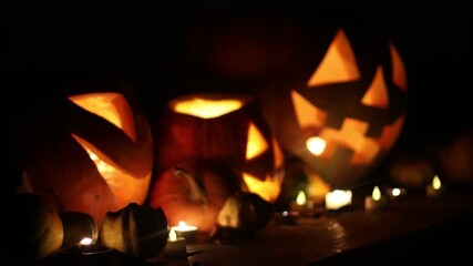 Happy Halloween. Jack o lantern glowing pumpkins with candles on table in dark scary backyard. Boo! Trick or treat! Spooky atmospheric Halloween night video - Powered by Adobe