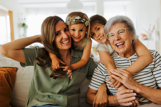 Three generations of women embracing and smiling at home
