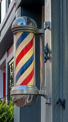 A red, white, and blue barber's pole hanging on a building’s facade