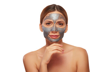 A woman with a charcoal mask on her face gently touches her chin, showcasing a moment of relaxation...