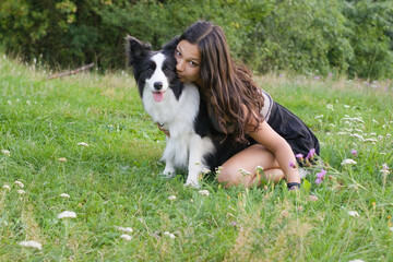 Obraz premium Young woman embracing Border Collie dog in meadow, leaning in with affection. Ideal for pet love themes, canine companionship visuals, and natural lifestyle portrait photography