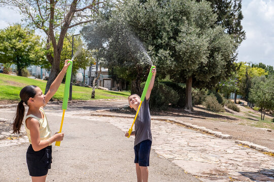 Kids Spraying Water Up With Foam Blasters On A Sunny Day
