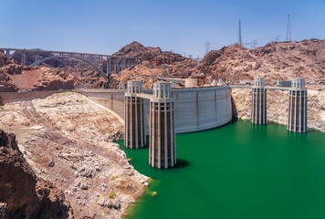 View of Hoover Dam showing low water levels in Lake Mead with the memorial arch bridge in background